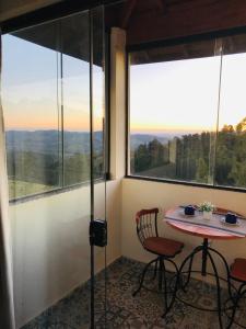 a room with a table and chairs and large windows at Chalé da Montanha - Locações in Águas de Lindóia