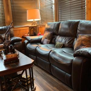 a living room with a leather couch and a table at HomeAway Cabins and Animal Sanctuary in Boerne