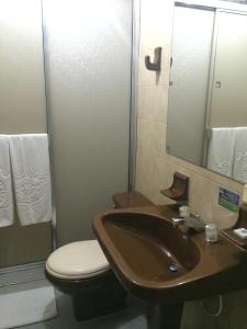 a bathroom with a sink and a toilet and a mirror at Hotel Tuvalu in Paipa