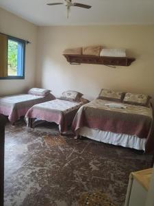 a room with three beds and a window at Hotel Fazenda Palestina in Itapecerica