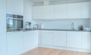 a white kitchen with white cabinets and appliances at New / Stunning Sea View / Light / 3 BR in Tórshavn