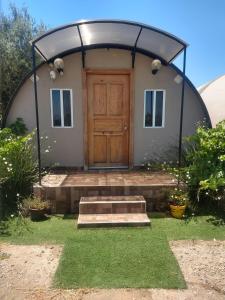 Casa con entrada redonda y puerta de madera en Cabañas Valle de Guadalupe, en La Amplación