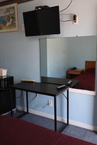 Elle comprend un bureau noir et une télévision murale à écran plat. dans l'établissement Economy Inn, à Lumberton
