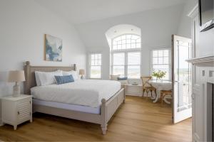 a white bedroom with a bed and a desk at Inn on the Beach in Harwich Port