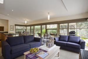 a living room with two blue couches and a table at Purfect Purnell in Anglesea