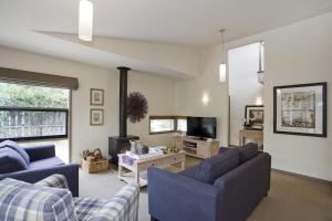 a living room with two blue couches and a tv at Purfect Purnell in Anglesea