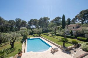 a swimming pool in a garden with a house at SERRENDY Villa with infinity swimming pool in Roquefort-les-Pins