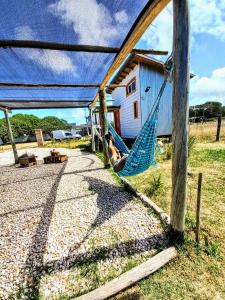 a woman laying in a hammock in front of a house at Tiny house Refugio santa isabel in Colonia Chapadmalal