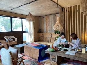 two women sitting at a table in a room at ゲストハウスよるよなか in Nagoya