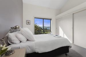 a white bedroom with a large bed with a window at Cape Vista 3 in Apollo Bay