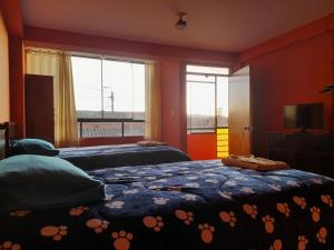 1 dormitorio con 2 camas, TV y ventanas en Hospedaje Encanto de Chinchero en Chincheros