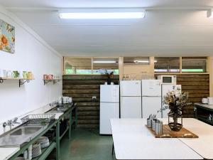 a large kitchen with white appliances and wooden walls at Iluka Retreat Glamping Village & Group Lodge Accommodation in Red Hill South