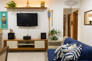 Casa azul Ilha Grande في أبراو: غرفة معيشة مع أريكة زرقاء وتلفزيون