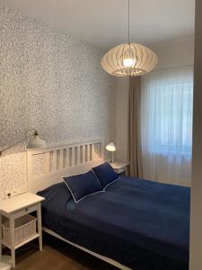 a bedroom with a blue bed and a chandelier at Vila MAY in Juodkrantė