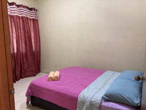 ein Schlafzimmer mit einem Bett mit einem Paar Schuhe darauf in der Unterkunft Lily Homestay @ Kangar, Perlis in Kangar