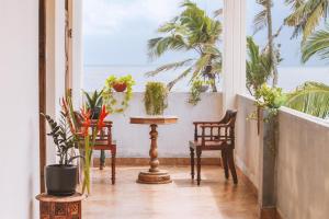 特里凡得琅的住宿－Santa Maria, Trivandrum - An Airport Boutique by the Sea，一间设有两把椅子和一张植物桌子的房间