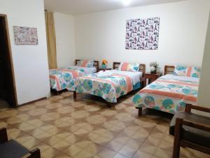 a room with three beds in a room at Hostal Cumbres Andinas in Ibarra