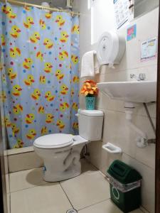 a bathroom with a toilet and a shower curtain at Hostal Cumbres Andinas in Ibarra