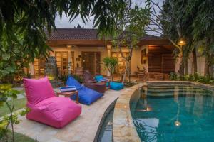 a backyard with a pool and chairs and a house at Bale Seminyak in Seminyak