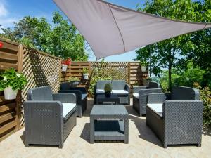 a patio with wicker chairs and a white umbrella at Belvilla by OYO Casale Verbena in Tavoleto