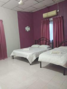 2 bedden in een kamer met paarse muren bij Hana Guesthouse in Kuala Tahan