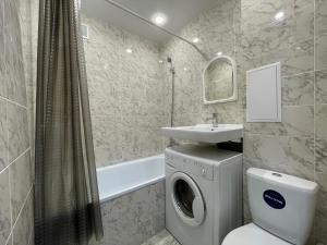 a bathroom with a washing machine and a sink at Квартира целиком с двуспальной кроватью и белым постельным in Petropavlovsk