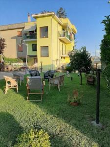 a yellow building with chairs and tables in the yard at Casa Vilu' in Paestum