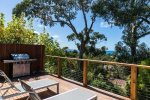 a deck with a grill and chairs and trees at Strathlea in Lorne