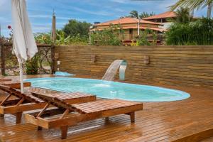 a swimming pool with a fountain and two chairs and an umbrella at Recanto Ancora Azul - Taipu de Fora in Barra Grande