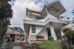 Casa blanca con balcón en una calle en Pall Inn Puncak Mitra RedDoorz, en Bogor
