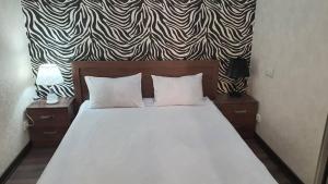 1 dormitorio con cama blanca y papel pintado en blanco y negro en Apartment studio with good view, en Bishkek