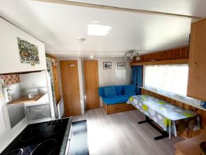 une petite chambre avec un canapé bleu dans une caravane dans l'établissement Bungalow de 2 chambres avec jardin amenage et wifi a Cauterets, à Cauterets