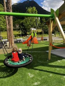 dos niños sentados en un columpio en un parque en Bungalow de 2 chambres avec jardin amenage et wifi a Cauterets, en Cauterets