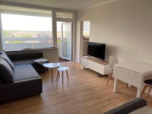 ein Wohnzimmer mit Sofa und Fernseher in der Unterkunft WEITBLICK APARTMENT direkt am Park mit kostenlosem Parkplatz in Bremerhaven