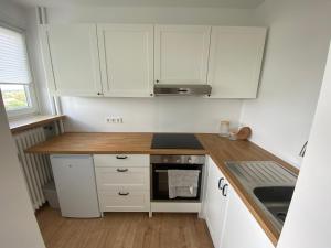 eine Küche mit weißen Schränken und einer Holzarbeitsplatte in der Unterkunft WEITBLICK APARTMENT direkt am Park mit kostenlosem Parkplatz in Bremerhaven