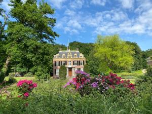 an old house in the middle of a garden with flowers at Appartement Osso Arnhem in Arnhem
