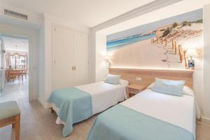 een kamer met 2 bedden en een schilderij van een strand bij Apartamentos Playa Marina in Cala Ferrera