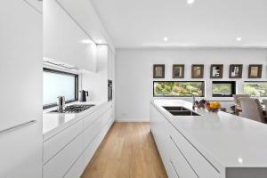 a white kitchen with white cabinets and a counter top at Oceania 11 in Lorne