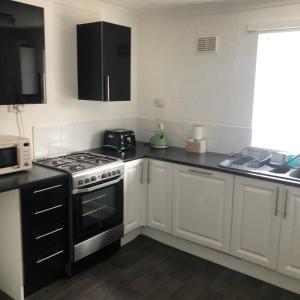 uma cozinha com armários brancos e um forno com placa de fogão em Normanby Raybould house em Normanby