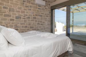 een wit bed in een kamer met een bakstenen muur bij AEONIOS LUXURY VILLA in Pitsidia