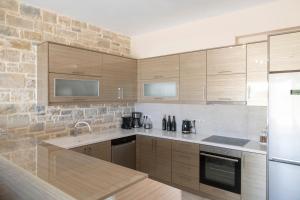 een keuken met houten kasten en een stenen muur bij AEONIOS LUXURY VILLA in Pitsidia