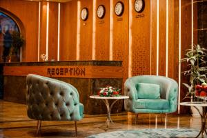 Regal Inn Badamdar Hotel في باكو: كرسيين وطاولة في غرفة بالساعات
