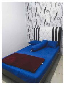 uma cama com lençóis azuis e almofadas azuis em Situ Gede Indah HOMESTAY em Tasikmalaya