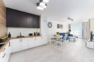 a kitchen with white cabinets and a dining room at Apartamenty Adyl Platany in Kołobrzeg
