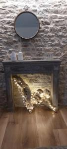 a fireplace with christmas lights in front of a stone wall at Gîte chez Marianne- la halte Jurassienne in Montmorot