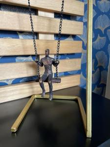 a metal man on a swing in front of books at Gîte chez Marianne- la halte Jurassienne in Montmorot