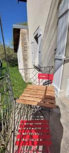 a wooden deck with a red bench next to a building at Gîte chez Marianne- la halte Jurassienne in Montmorot