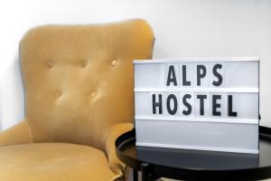 una sedia seduta accanto a un tavolo con un cartello di Alps Hostel a Pfronten