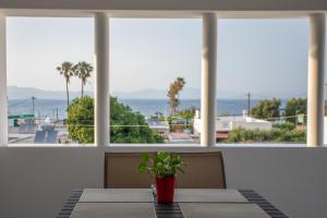 un tavolo con una pianta in vaso di fronte a una finestra di On The Breeze 1 a Città di Kos