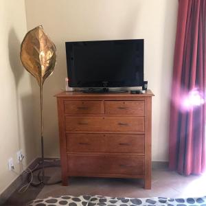 a television on top of a dresser with a lamp at Wine Cottage by the Sea in Helderberg +12 photos